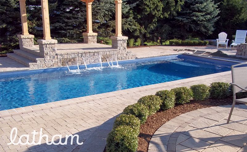 Rectangular fibreglass pool with a raised stone spa and three sheer-descent spillways under stone columns