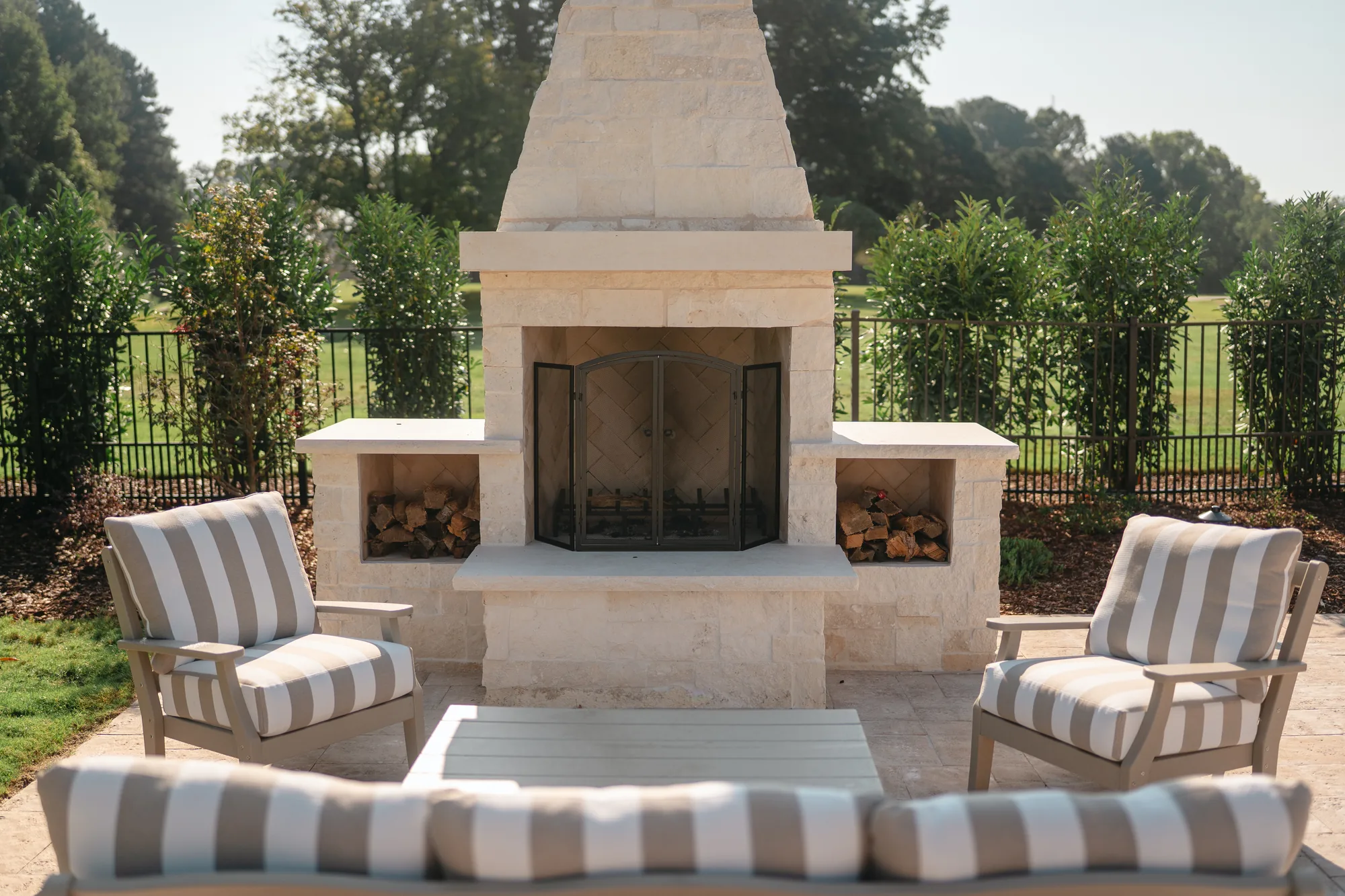 White limestone outdoor fireplace and chimney on a travertine patio overlooking open lawn in Guntersville, Alabama
