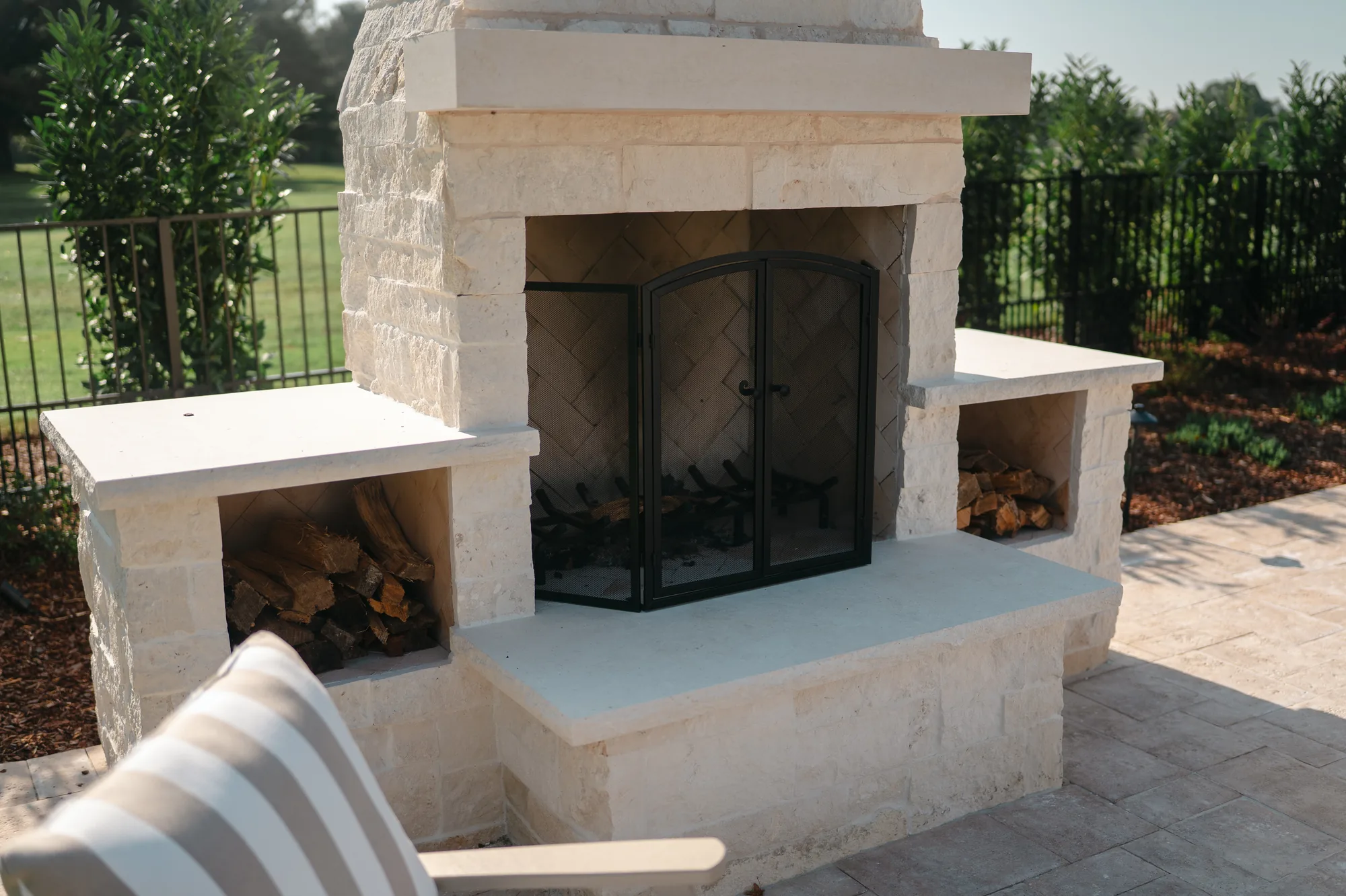 Outdoor limestone fireplace with a herringbone firebox and built-in firewood storage in Guntersville, Alabama