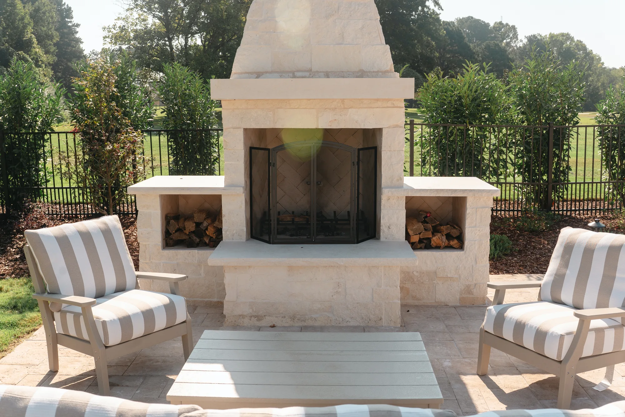 Travertine patio seating area with a white limestone outdoor fireplace in Guntersville, Alabama