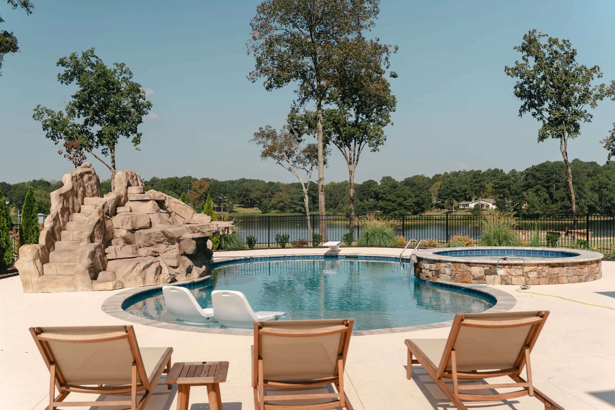 Oval pool with a rock waterslide and round raised spa overlooking Lake Catoma in Cullman, Alabama