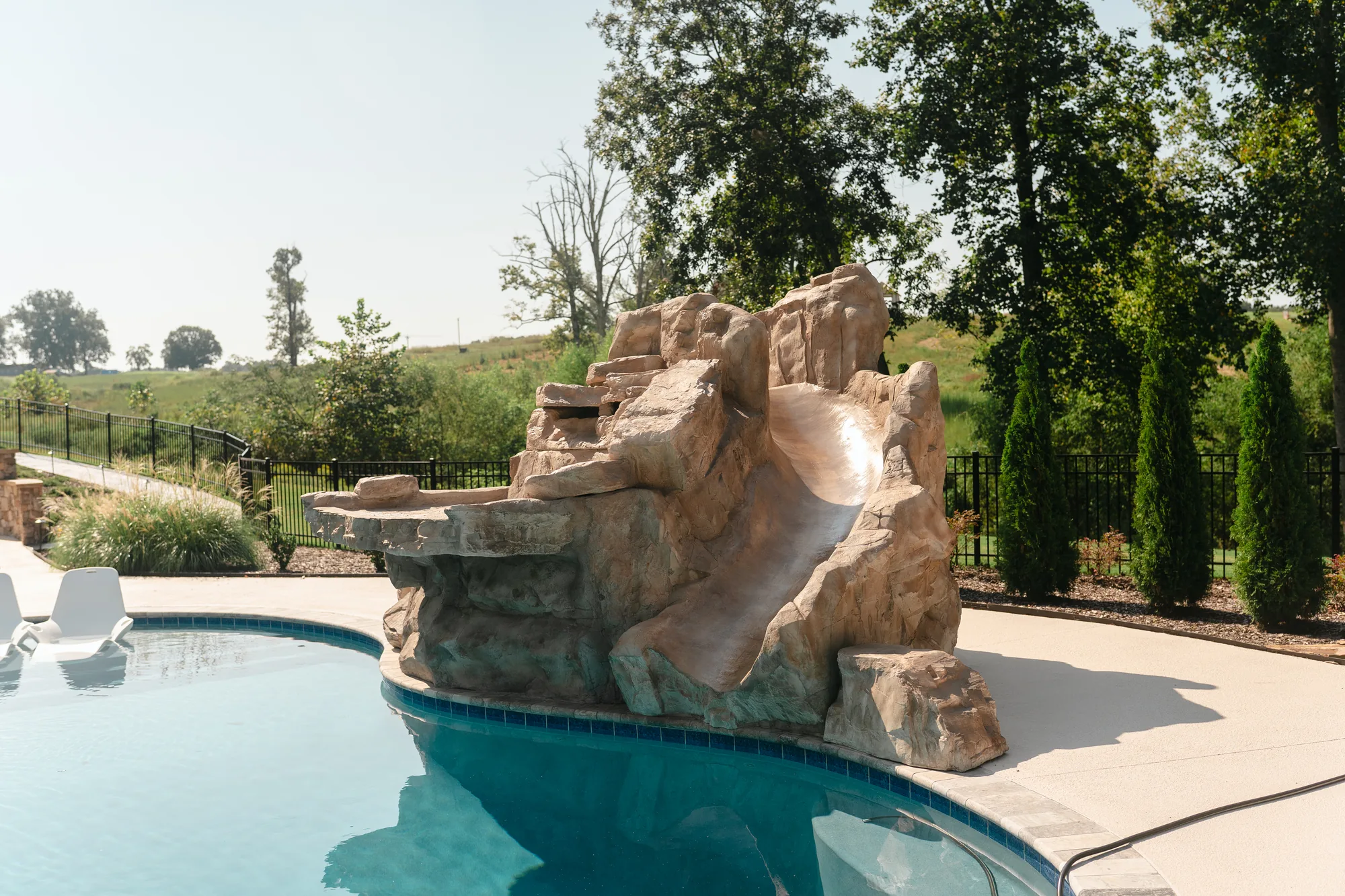 Sculpted rock waterslide and grotto feature built into the edge of a pool in Cullman, Alabama