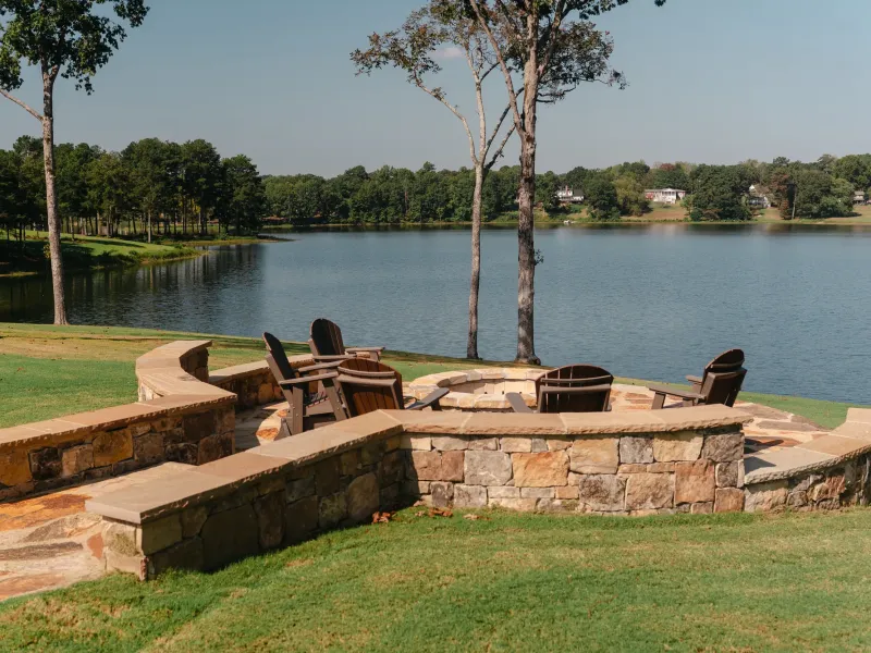 Lakeside stone fire pit with a curved seat wall and mortared flagstone patio overlooking Lake Catoma in Cullman, Alabama
