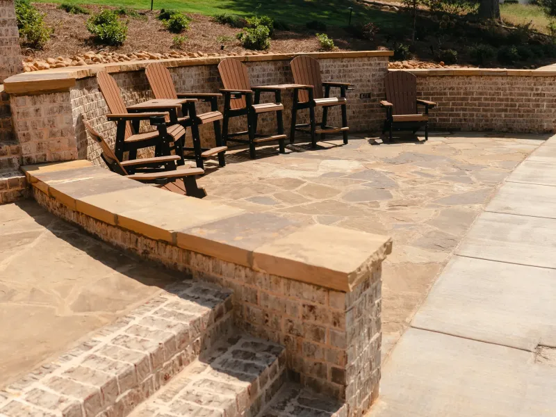 Flagstone patio enclosed by brick seat walls with thick sandstone caps and bar-height chairs, above Wheeler Lake in Athens, Alabama