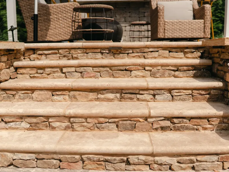 Travertine treads on dry-stacked stone risers rising to a covered seating area in Madison, Alabama