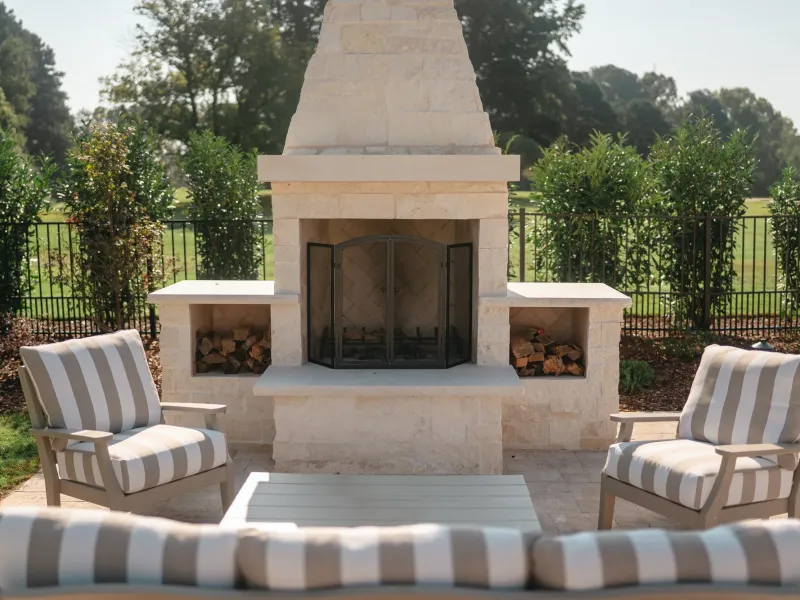 White limestone outdoor fireplace and chimney on a travertine patio overlooking open lawn in Guntersville, Alabama