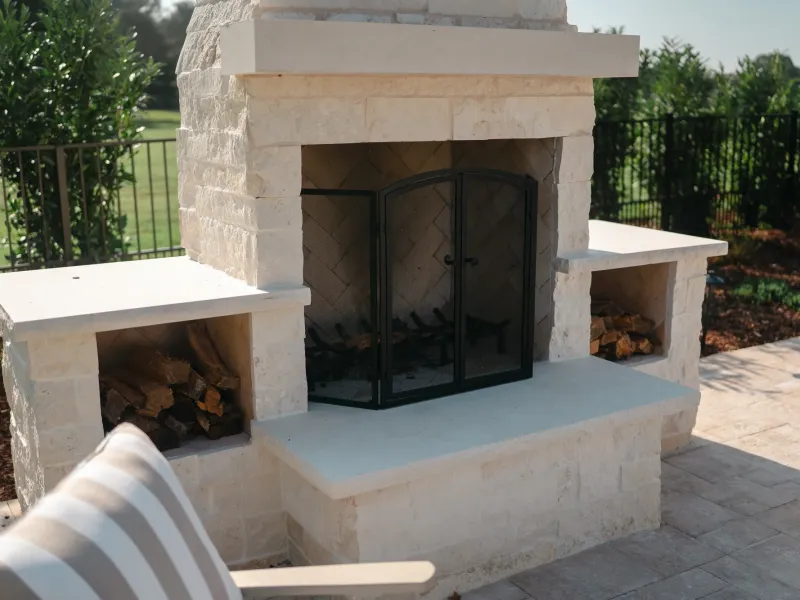 Outdoor limestone fireplace with a herringbone firebox and built-in firewood storage in Guntersville, Alabama