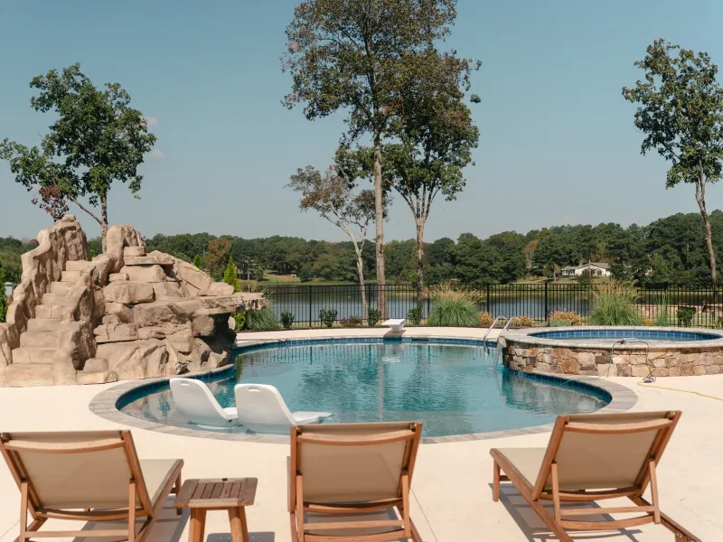 Oval pool with a rock waterslide and round raised spa overlooking Lake Catoma in Cullman, Alabama