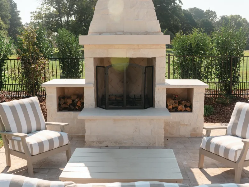 Travertine patio seating area with a white limestone outdoor fireplace in Guntersville, Alabama